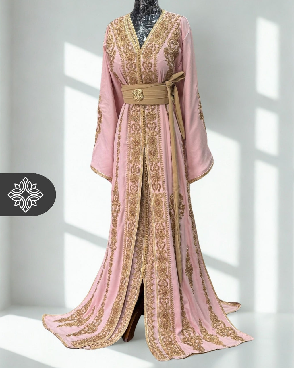 Pink kaftan dress with gold embroidery on a mannequin against a white background